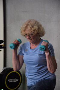 Vrouw van vijftig-plus traint met dumbbells om haar spiermassa te behouden