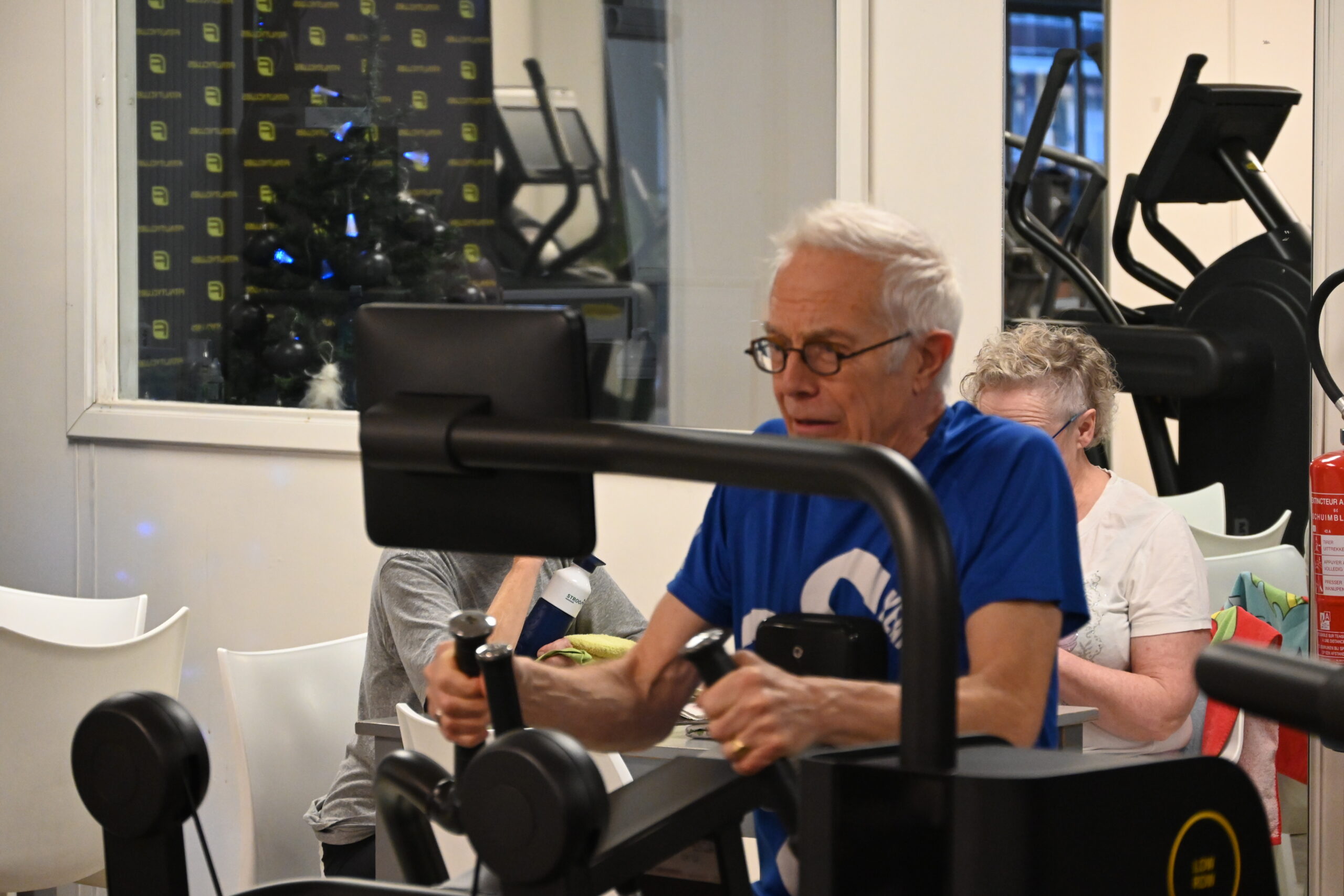 Man roeit in een beheerst tempo op het roeitoestel bij Fitality