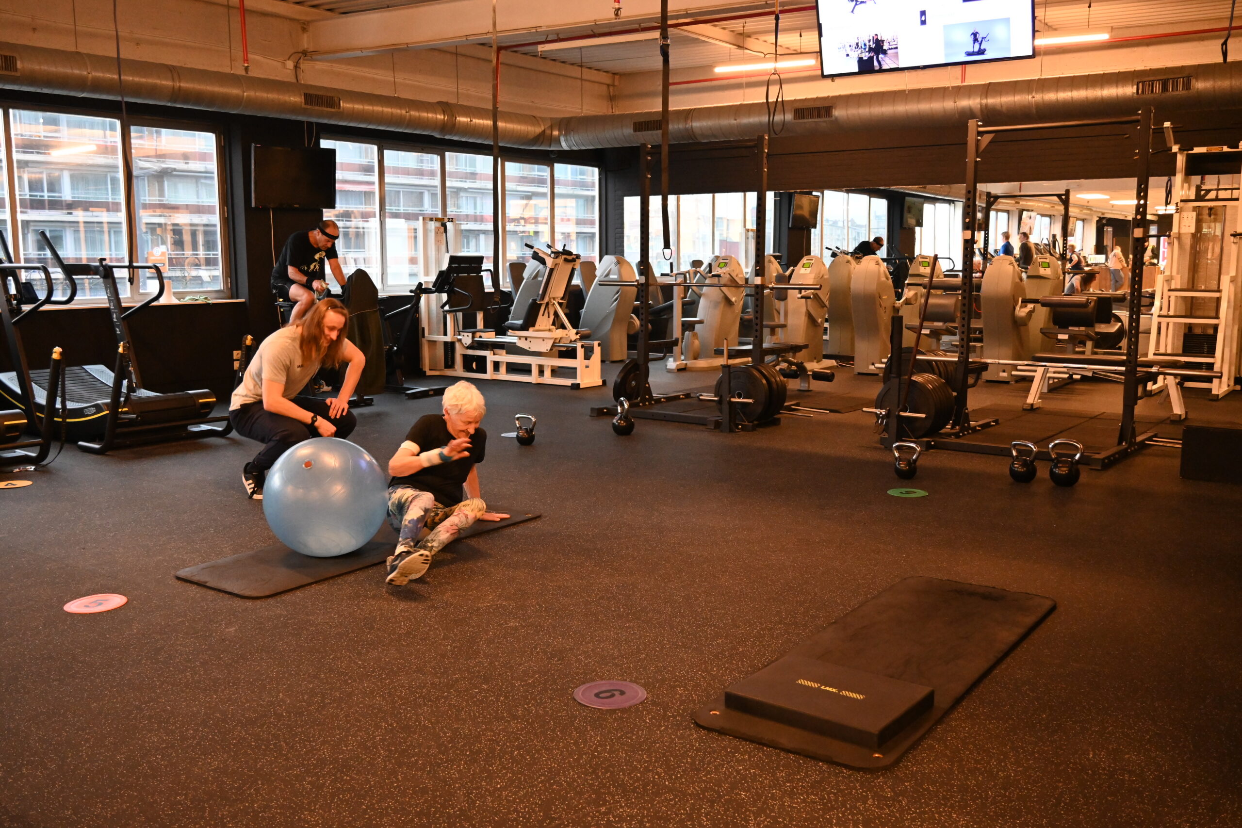 Coach begeleidt iemand die begint met sporten bij een oefening met de fitnessbal