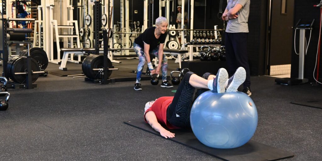 Coach begeleidt een oudere dame bij een kettlebell-oefening voor sterkere botten