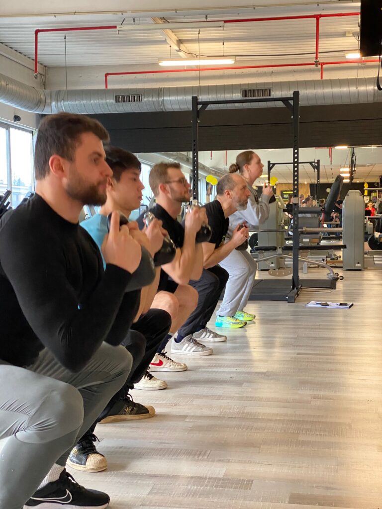 Oudere man doet een kettlebell deadlift tijdens een groepstraining bij Fitality