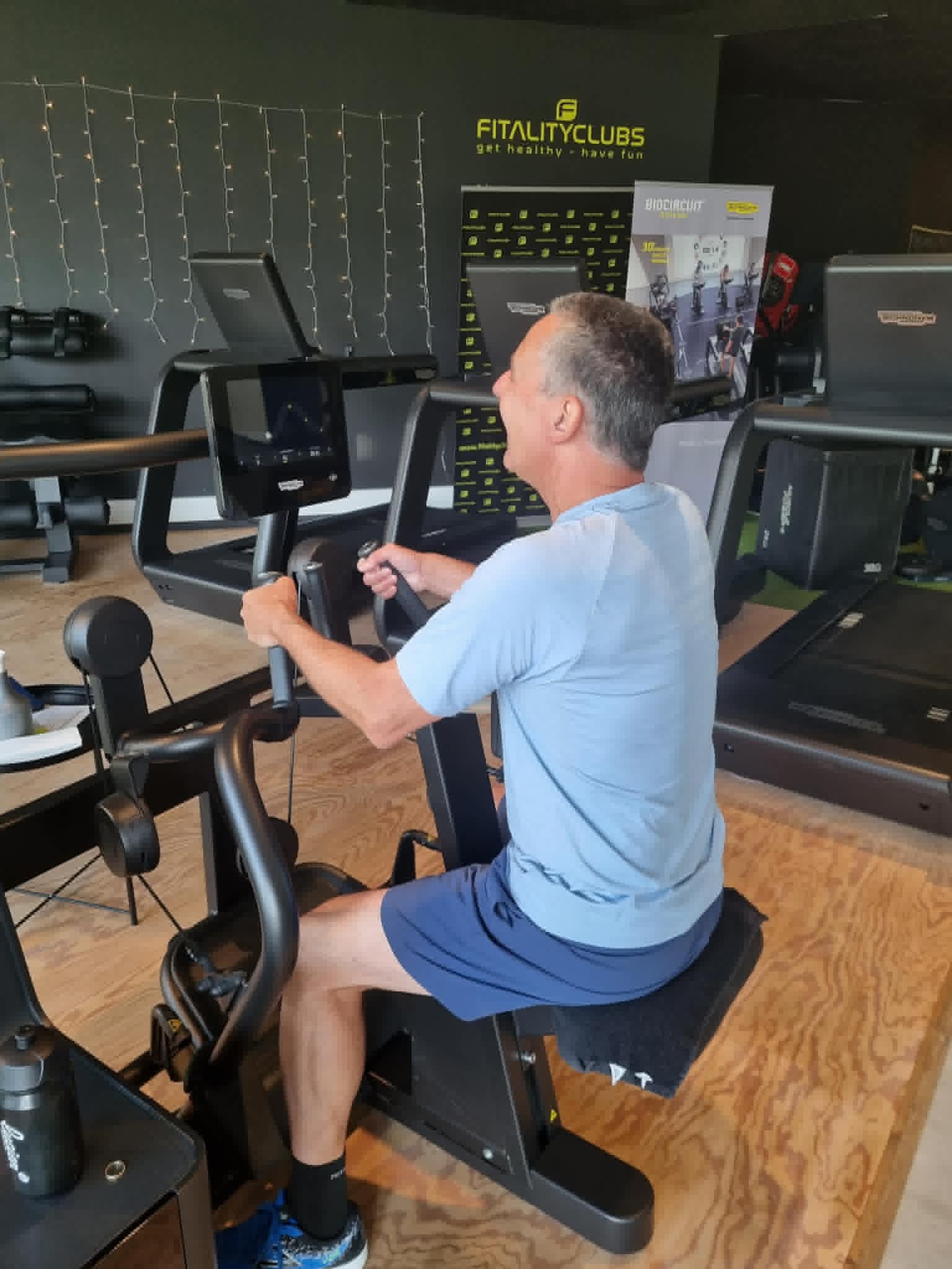 Man traint rustig op het fietstoestel in het circuit bij Fitality