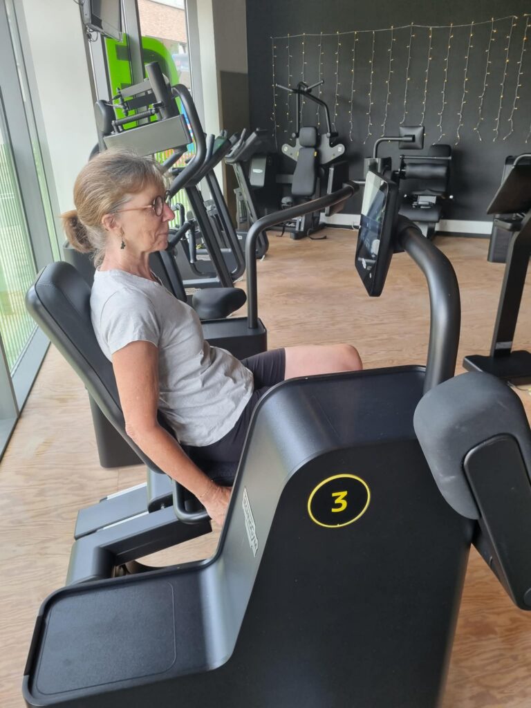 Vrouw van boven de 45 traint haar benen op de beenpers bij Fitality