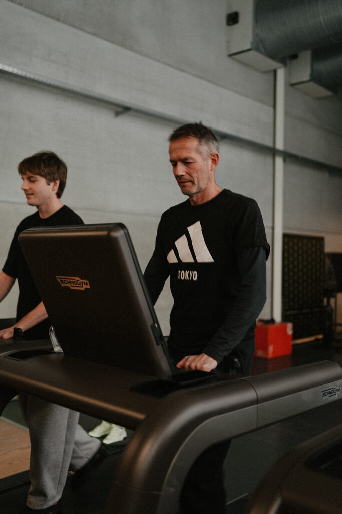 Man van 45 traint samen met een trainingspartner op de loopband bij Fitality