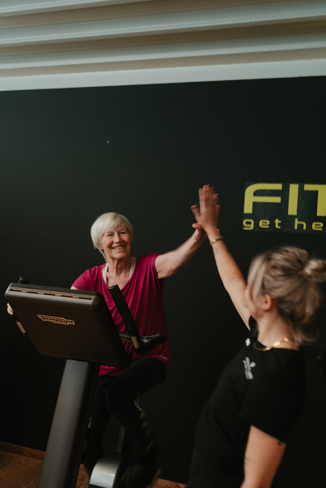 Vrouw geeft haar coach een high five na een fietssessie bij Fitality