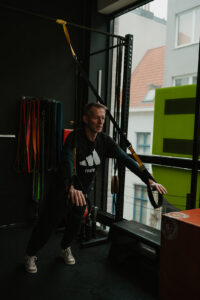 Man van midden veertig traint met TRX-banden na een werkdag aan het bureau