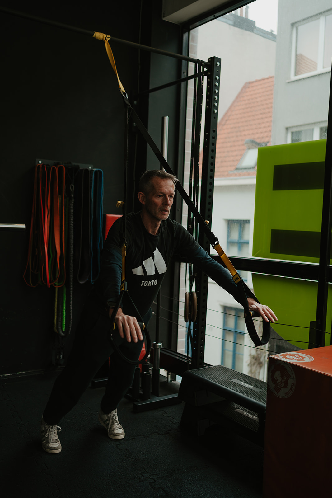 Man van midden veertig traint met TRX-banden na een werkdag aan het bureau