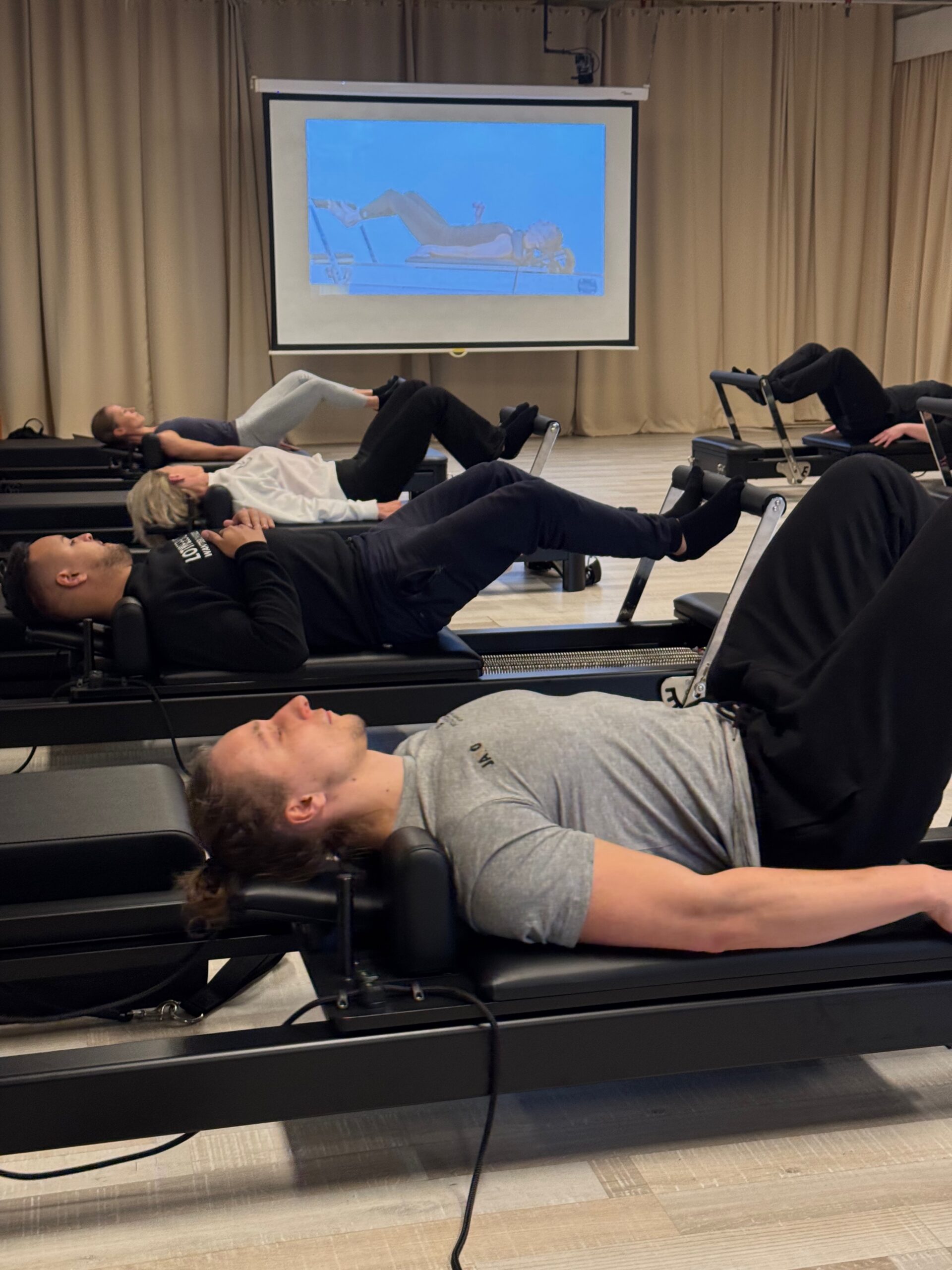 Vrouw traint liggend haar core op de Reformer tijdens een pilatesles bij Fitality Deurne